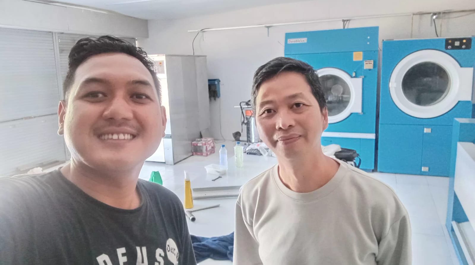 Diskusi proses laundry di depan mesin pengering komersial